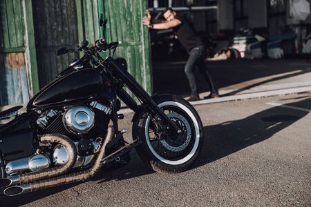 Adult biker is closing door in garage