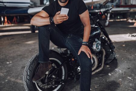 Cropped photo of biker texting on cell phone on motorcycle. Digital technology conceptの写真素材