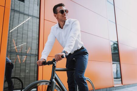 Jolly young man is cycling to workの写真素材