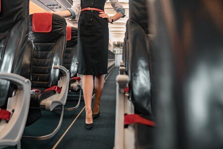 Caucasian stewardess walking in aisle of airliner stock photo. Airways conceptの写真素材