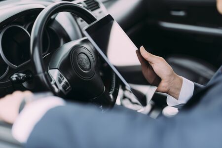 Close up of male in suit holding touch pad near wheelの写真素材