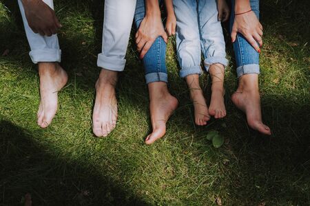 Legs of father, mother and daughter on green grass. Family conceptの写真素材