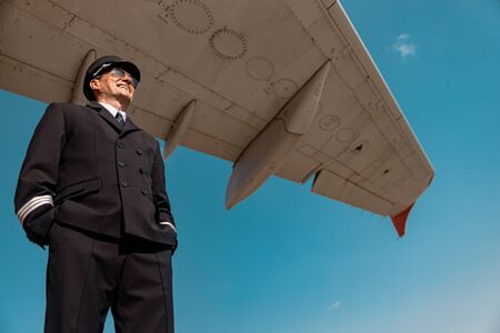 Mature Caucasian pilot in costume smiling outdoors stock photo. Airways conceptの写真素材