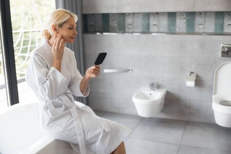 Attentive woman looking at her little mirrorの写真素材