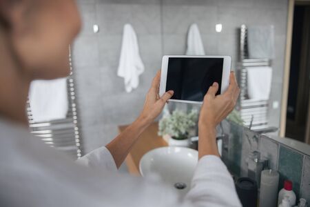 Clean glass. Charming female person being in bathroom and taking photo of her beauty cornerの写真素材