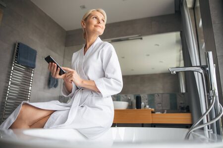 Positive delighted blonde staring at big windowの写真素材