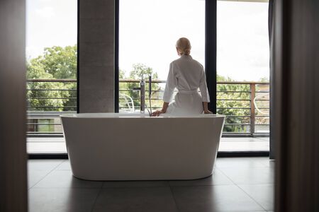 Relaxed blonde woman looking at big windowの写真素材