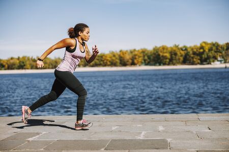 Beautiful Afro American woman running by the river