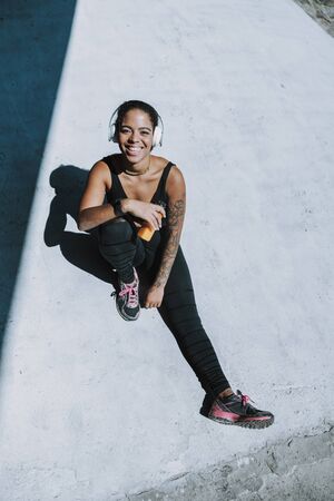 Cheerful Afro American girl in headphones resting outdoorsの写真素材