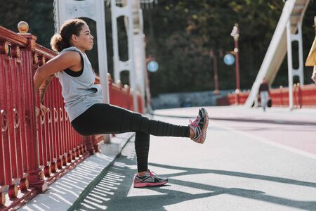 Athletic Afro American lady doing exercise on the bridge