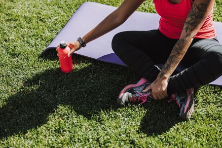 Young woman sitting on yoga mat outdoorsの写真素材