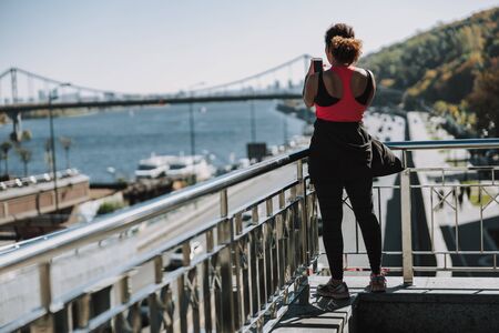 Young woman in sportswear using cellphone on the street stock photoの写真素材