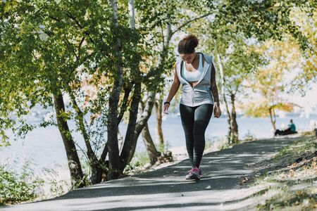 Afro American young woman in sportswear strolling through the park stock photoの写真素材