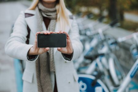 Young female using smartphone and showing empty displayの写真素材