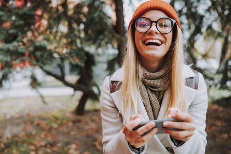 Young woman holding modern smartphone in handsの写真素材