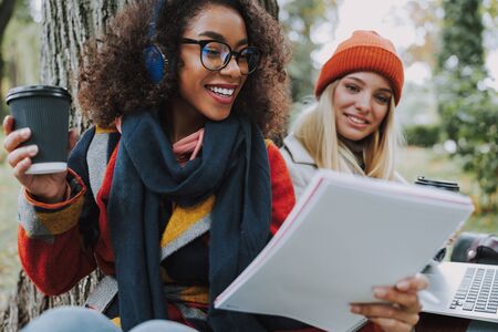 Two pretty women making homework for university outdoors