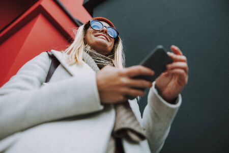Glad woman with smiling face near red building wall stock photoの写真素材