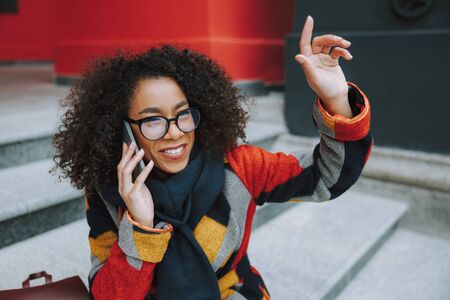 Afro American woman talking on smartphone and waving handの写真素材