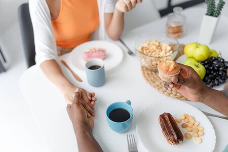 Happy young couple holding hands in cafeの写真素材
