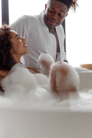 Cute young lady looking at her boyfriend while taking bathの写真素材