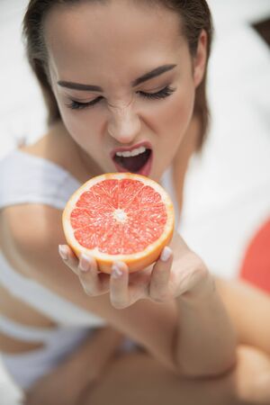 Pretty young lady going to bite a grapefruitの写真素材
