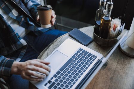 Cropped photo of Caucasian guy using laptop for work in cafe. Business conceptの写真素材