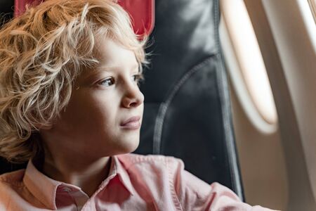 Little boy is sitting near window in planeの写真素材