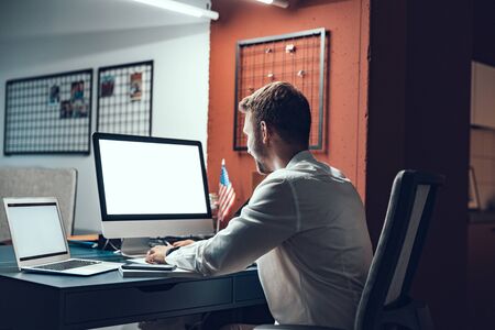 Smiling young man is typing on computerの写真素材