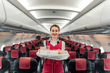 Pretty smiling stewardess standing with food in cabinの写真素材