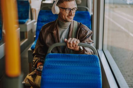 Handsome gentleman listening to music in public transportの写真素材