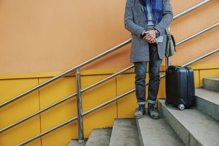 Elegant young man in coat holding cellphoneの写真素材
