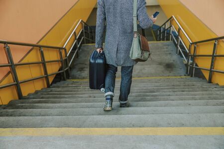 Elegant man walking down the stairs and using cellphoneの写真素材