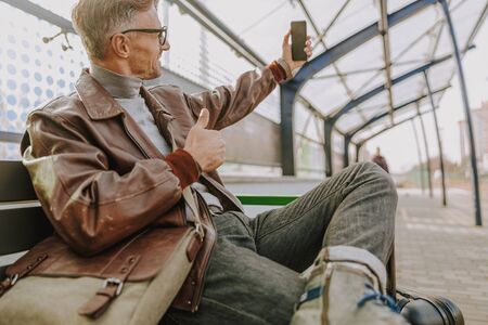 Handsome man doing thumbs up and making selfie outdoorsの写真素材
