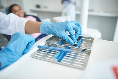 Dentist is using implements for check-up in office