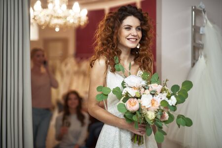 Bride in white dress posing with flower bunchの写真素材
