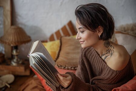 Happy pretty lady looking on book in bedroom