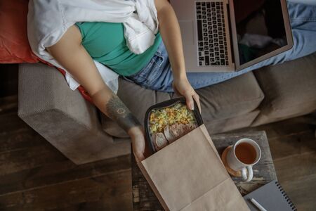 Busy girl taking food from the packageの写真素材