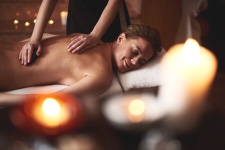 Young lady have relaxing massage with warm stonesの写真素材