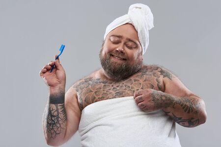 Adorable funny man smiling and holding blue toothbrushの写真素材