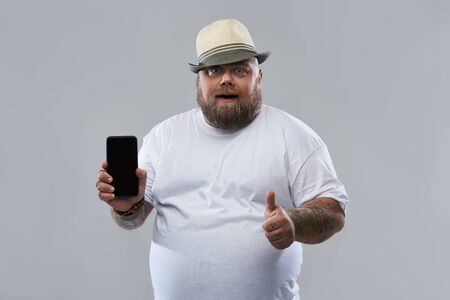 Happy man with smartphone putting thumb up and smiling