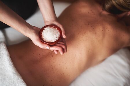 Massage therapist hold bowl with mineral saltの写真素材