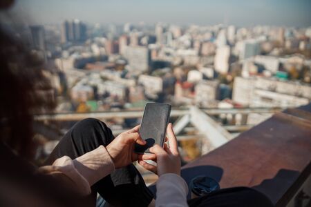 Close up of female hands with mobile phone on roofの写真素材