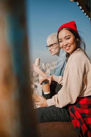 Happy Asian lady holding coffee on the roofの写真素材