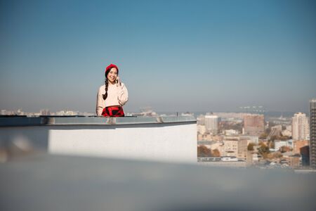Pretty smiling lady using smartphone while staying on roofの写真素材