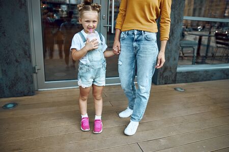 Happy girl holding hand of mother and drinking milkshake stock photo
