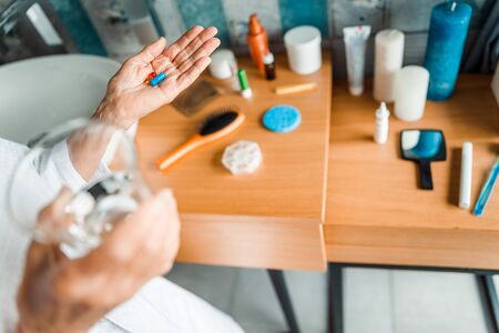 Senior woman holding pills and glass of waterの写真素材