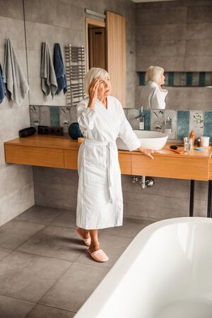 Upset old woman in bathrobe having headacheの写真素材