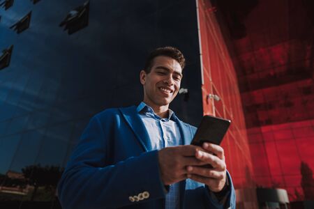 Happy man using smartphone in city stock photoの写真素材