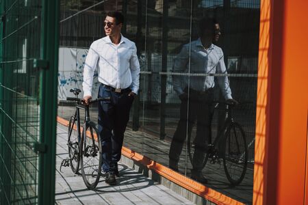 Smiling executive using bicycle in city stock photoの写真素材
