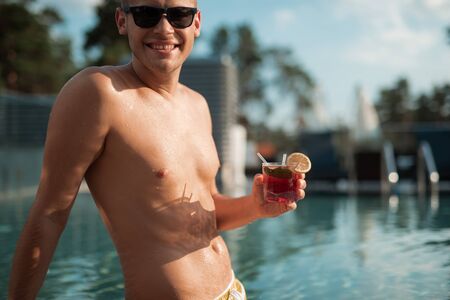 Joyful sexy guy holding glass of cocktailの写真素材